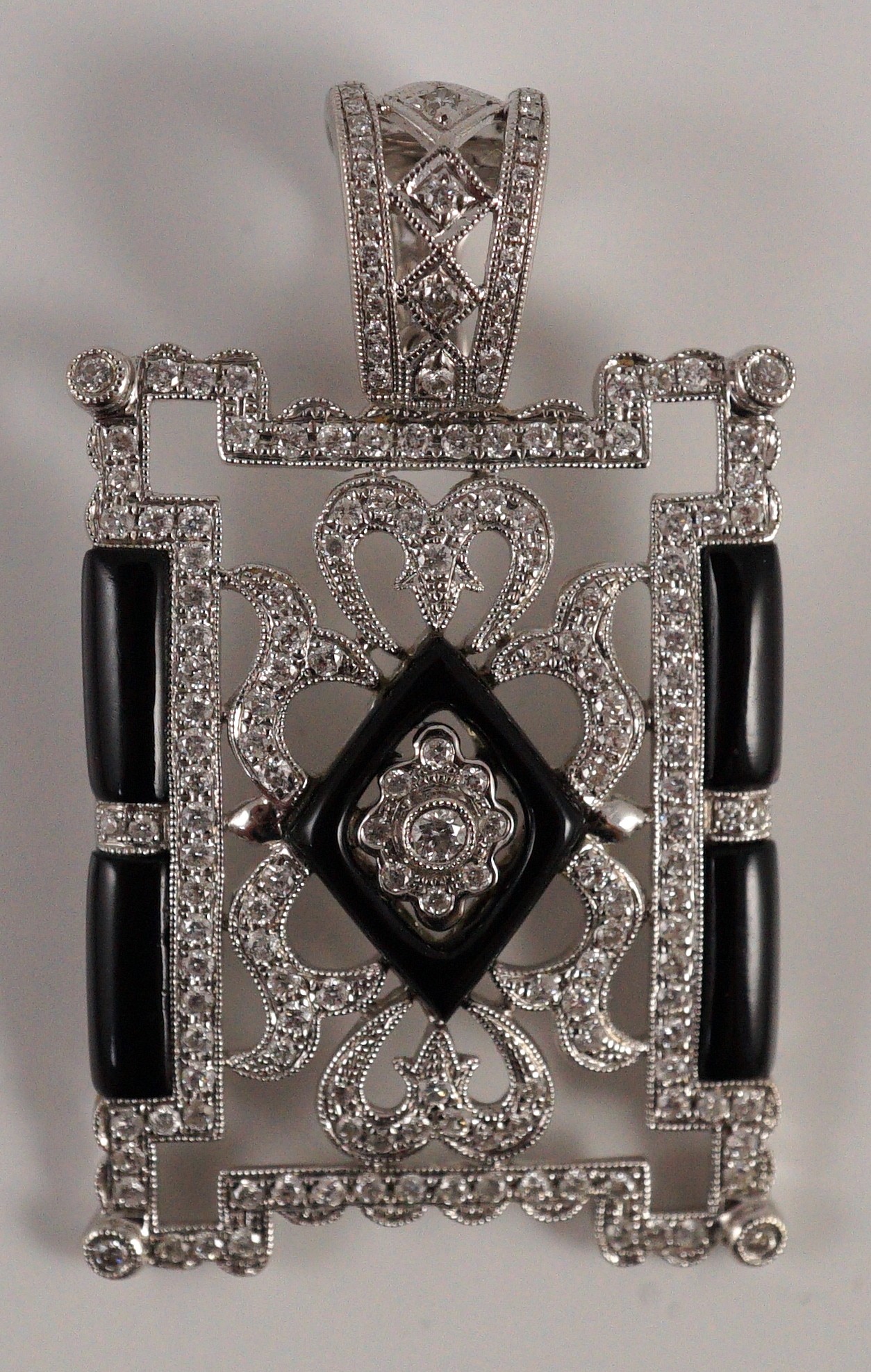 A modern 1920's style pierced 18k white gold, diamond and black onyx set rectangular pendant